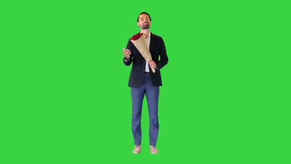 Handsome Man in a Suit Talking To Camera Holding Red Roses on a Green Screen Chroma Key