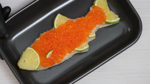 Sandwich with red caviar in shape of fish with lemon. Expensive healthy food concept