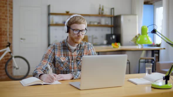 Student in Headphones Studying on Computer Sitting at Home