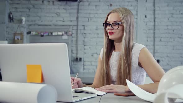 Smart Young Woman Working on Modern Laptop and Speaking