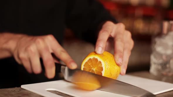 Bartender slicing orange to use in mixed drink