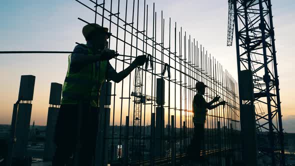 Construction Workers Are Making a Metal Framework at Sunset alt