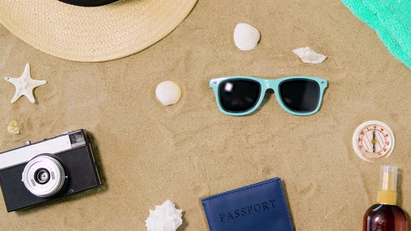 Camera, Passport, Sunglasses and Hat on Beach Sand