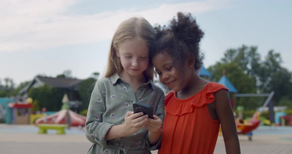 Medium Shot of Multiracial Kids Using Cellphone at Playground