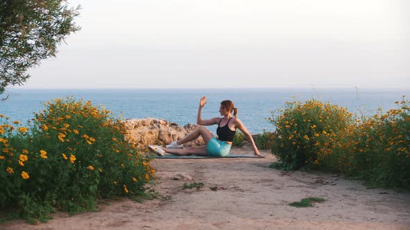 A Woman in Sportswear Exercising on Yoga Mat By the Sea