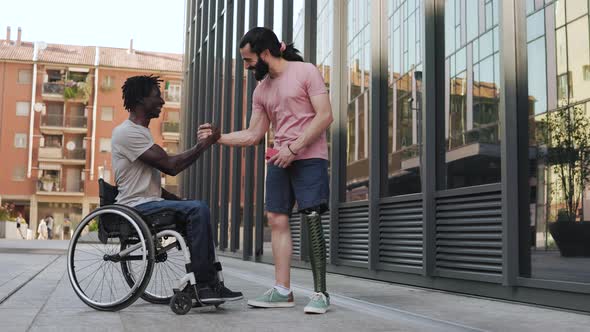 Diverse friends with physical disabilities having fun shaking hands outdoor in city