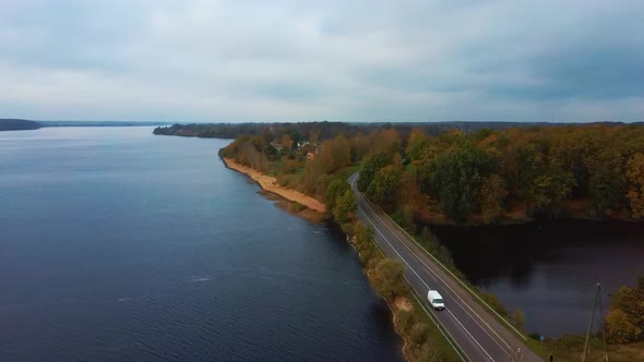 Aerial View of Colorful Forest and Trafic Road at River Daugava in Latvia. Autumn Landscape. 4K Vide