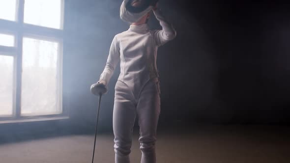 A Young Woman Fencer Putting on a Protective Helmet and Gets Into Position for the Fight