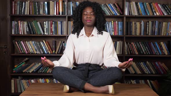 Concentrated Afroamerican Businesswoman Meditates on Table