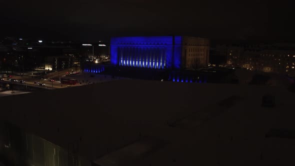 Winter night aerial rises over Helsinki Parliament House, blue lights