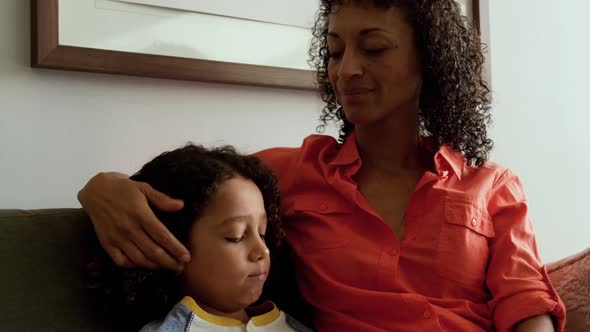 Front view of African american mother consoling her son in the lobby at hospital 