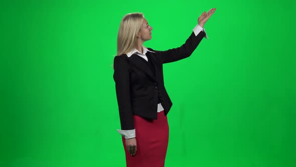 Beautiful Woman Showing Something Standing Against Green Screen Chroma Key Background.