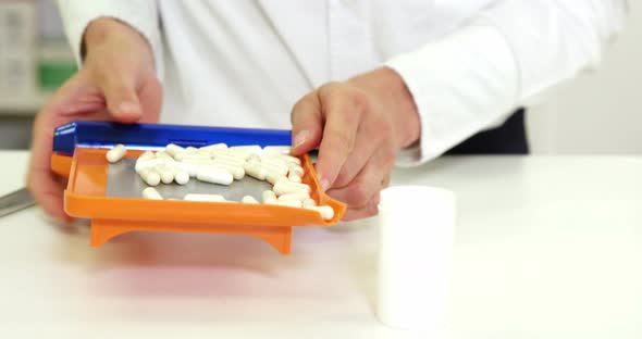 Pharmacist putting pill in container at pharmacy