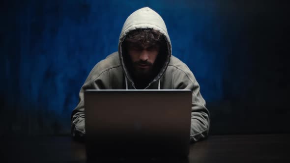 Portrait of Thoughtful Hacker Man Looking at Laptop Screen Thinking Solving Problem at Dark Room