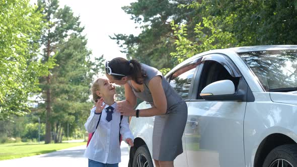 Mother Putting Schoolbag on Daughter Near Car