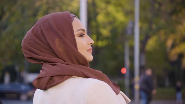 A Young Beautiful Muslim Woman Looks Over Her Shoulder in a Street in an Urban Area  Closeup