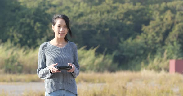 Woman controling flying drone in the park