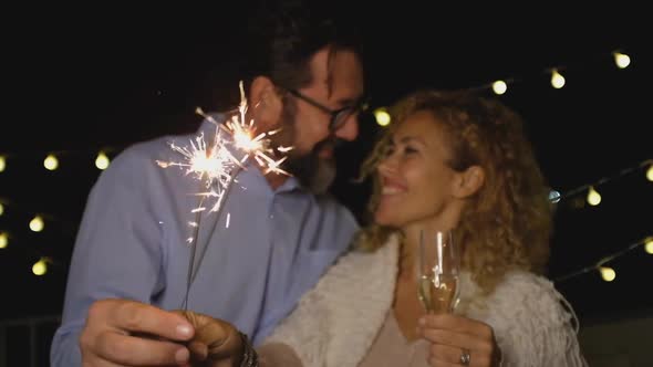 cute couple of two adults in love giving a loss together the new year night playing with sparklers