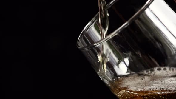 Light Beer Is Poured Slowly Into a Glass on a Black Background
