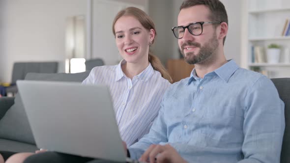 Cheerful Young Couple Doing Video Call on Laptop at Home