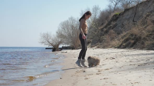 Smiling Young Woman Trains Small Shih Tzu Puppy Running