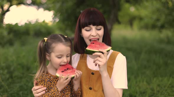 Beautiful Mom and Her Daughter Holding Pieces of Watermelon While Resting at Picnic at the Park