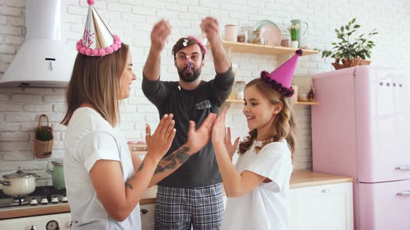 Happy Family in Pajamas with a Daughter Dancing and Celebrating Birthday in Kitchen During Online