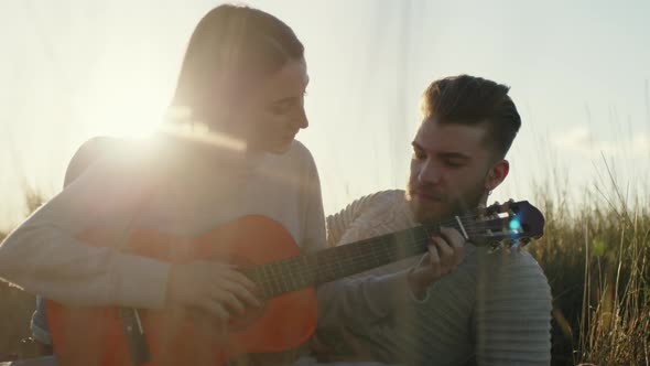 Boy and Girl Playing the Guitar in the Countryside