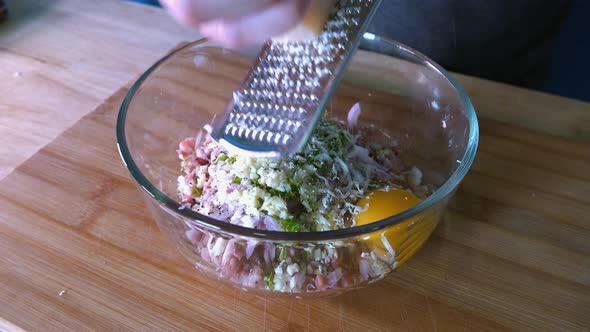 Grating Parmesan into Meatball Mixture in a Glass Bowl