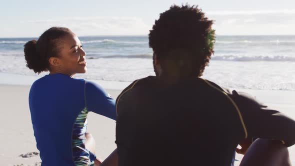 African american couple talking and sitting on the beach