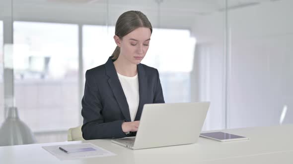 Serious Young Businesswoman Working on Laptop in Office