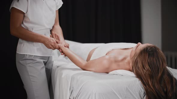 Young Woman Having a Massage Session in the Cabinet Lying on the Couch While the Masseuse Massaging