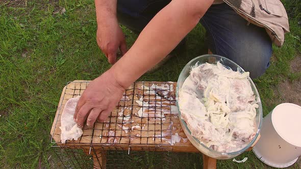 The Man Lays Out the Marinated Cuts of Meat on the Wire Rack