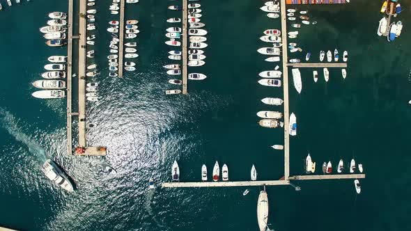 White Motorboat Sails From the Pier with Moored Yachts