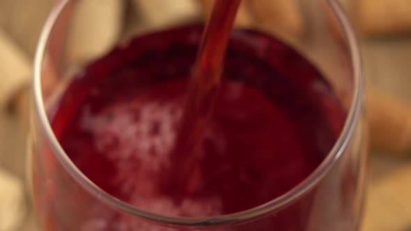 Wine is poured into a glass on the background of wine corks.