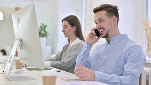 Happy Creative Man Talking on Smart Phone in Office