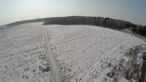 Village with vast snowy fields near the forest, aerial view