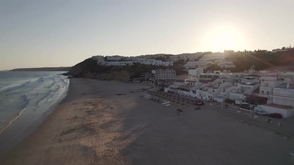 Sunset by the beach, Salema, Algarve. Sun kissed waves washing on the sand. Arerial view