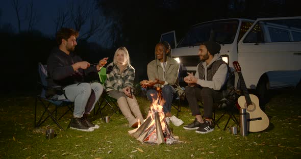 Four Young Tourists are Sitting on Chairs By the Fire