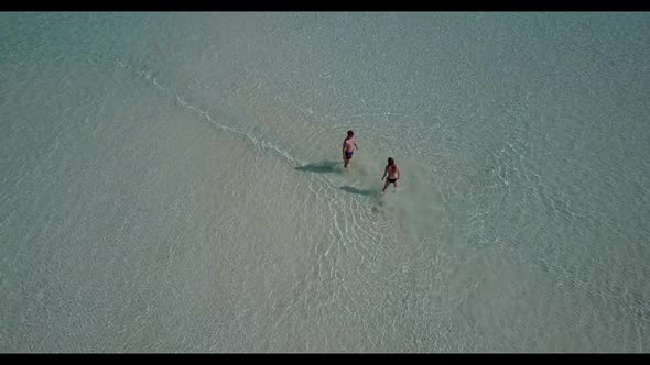 Family of two sunbathe on beautiful tourist beach holiday by blue ocean and white sand background of