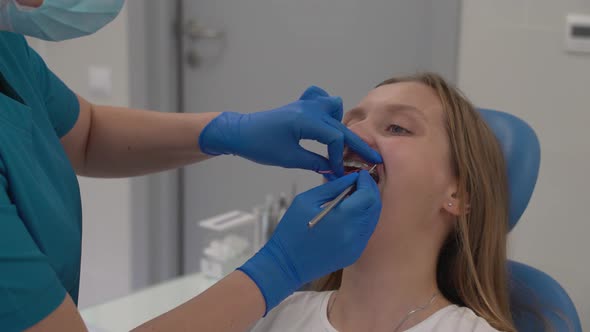 Orthodontist Fixes the Elastic Bands on the Braces with Tool