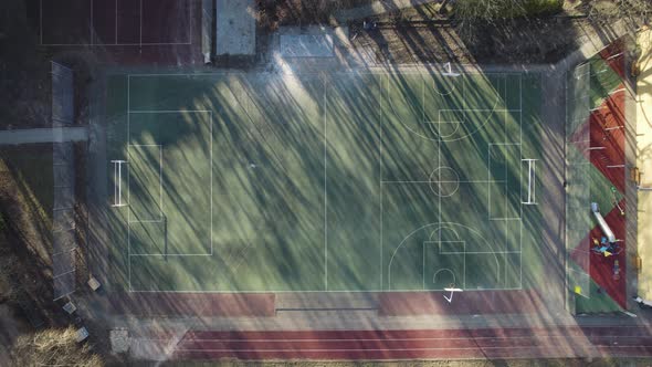 Soccer Grass Pitch during a Sunshine Afternoon, Aerial Drone View surrounded by Trees and Houses