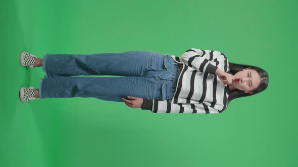 Full Body Of A Smiling Asian Woman Saying Shh While Standing In Front Of Green Screen Background