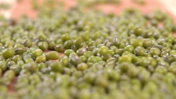 Organic farm raw green mung beans falling in slow motion on a wooden cutting board