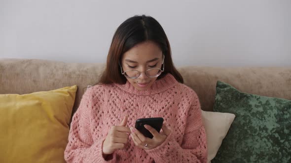 Middle Eastern Young Female Sitting on the Sofa in the Living Room with a Smartphone and Buying