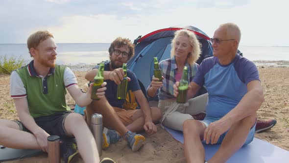 Group of Friends Cheering with Beers at Barbecue Dinner on the Beach