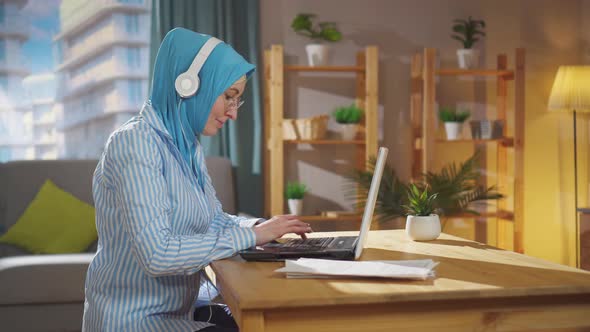 Young Muslim Freelancer in a National Headscarf Works at a Laptop Sitting in the Living Room