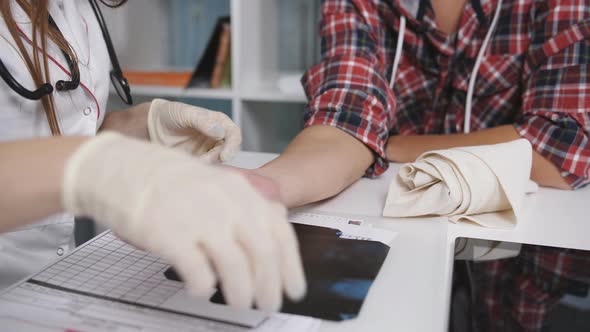 Close Up of Male Patient Hand and Wrist with Doctor Explaining x Ray on Tablet