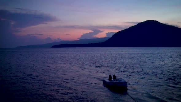 the sun is rising behind a mountain. view is from a boat rocking in the bay in alor