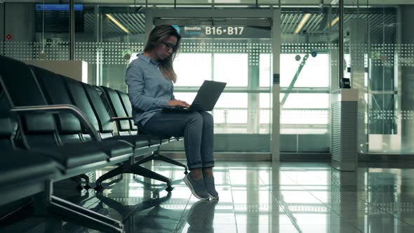 Empty Departure Lounge with a Lady Operating a Laptop